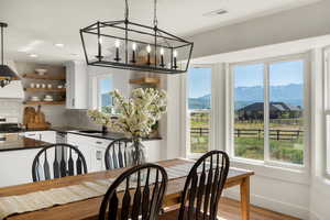 Dining room with a mountain view, wood finished floors, a chandelier, baseboards, and recessed lighting