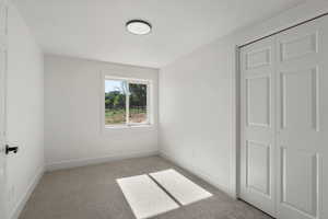 Empty room featuring light colored carpet and baseboards