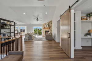 Living area with vaulted ceiling, a barn door, ceiling fan, wood finished floors, and recessed lighting