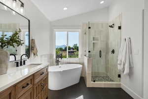 Bathroom featuring lofted ceiling, a stall shower, vanity, a freestanding tub, and tile patterned floors