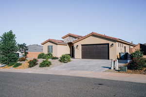 Mediterranean / spanish-style house with stucco siding, an attached garage, a tile roof, and concrete driveway