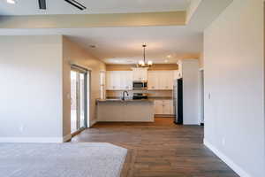 Kitchen with stainless steel appliances, white cabinets, a peninsula, recessed lighting, and baseboards