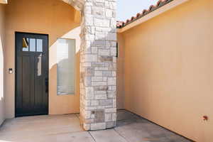 View of exterior entry with stucco siding and a tiled roof