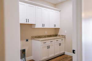 Laundry area with cabinet space, dark wood-style floors, baseboards, and electric dryer hookup