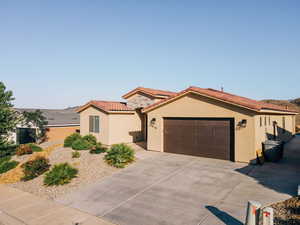 Mediterranean / spanish-style home featuring an attached garage, stucco siding, driveway, and a tiled roof