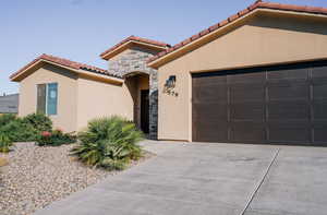 Mediterranean / spanish home featuring driveway, stone siding, a tile roof, stucco siding, and an attached garage