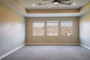 Carpeted spare room featuring baseboards, recessed lighting, ceiling fan, and a raised ceiling