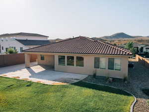 Rear view of house with stucco siding, a tile roof, a patio, and a mountain view