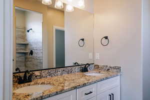 Bathroom featuring double vanity and tiled shower