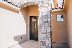 Entrance to property with stone siding and stucco siding