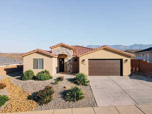 Mediterranean / spanish house with stucco siding, a garage, concrete driveway, a tile roof, and a mountain view