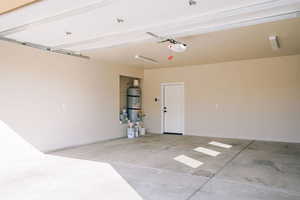 Garage featuring water heater, a garage door opener, and baseboards