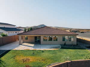 Rear view of property featuring stucco siding, a tiled roof, and a patio area