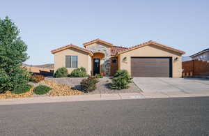 Mediterranean / spanish-style house with stucco siding, a tile roof, an attached garage, driveway, and stone siding