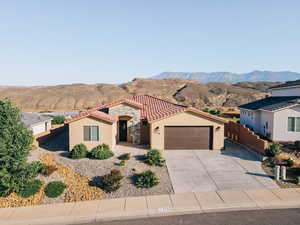 Mediterranean / spanish house featuring an attached garage, stucco siding, a mountain view, a tile roof, and driveway