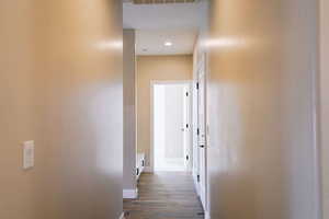 Hallway featuring baseboards, dark wood-type flooring, and recessed lighting