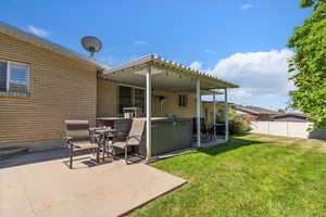 Back of house with a hot tub, a patio, and brick siding
