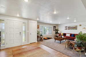 Entrance foyer featuring a textured ceiling, light wood-type flooring, recessed lighting, and baseboards