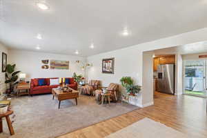 Living area featuring light wood-style flooring, a textured ceiling, recessed lighting, and baseboards