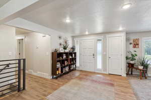 Foyer entrance featuring a textured ceiling, light wood finished floors, baseboards, and recessed lighting