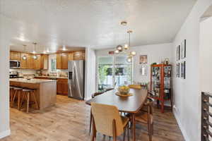 Dining area featuring light wood-style flooring, plenty of natural light, baseboards, and a textured ceiling