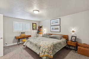 Bedroom with carpet flooring, baseboards, and a textured ceiling