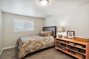 Carpeted bedroom featuring a textured ceiling and baseboards