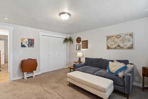 Carpeted living area with a textured ceiling and baseboards