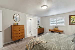Bedroom with carpet flooring, baseboards, and a textured ceiling