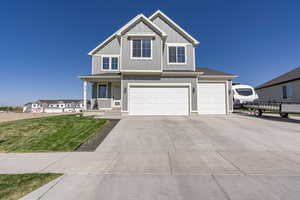 View of front of home featuring board and batten siding, driveway, a front yard, an attached garage, and a porch