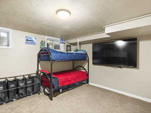 Carpeted bedroom with a textured ceiling and baseboards