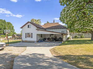 View of front of house featuring concrete driveway, a front lawn, a chimney, a carport, and roof with shingles