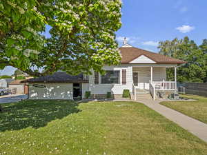 Bungalow with covered porch, an attached garage, a shingled roof, and a chimney