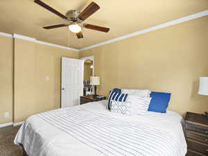 Carpeted bedroom featuring ornamental molding and ceiling fan