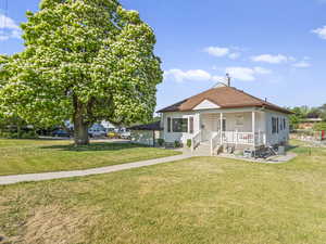 Bungalow featuring a front yard, roof with shingles, and covered porch