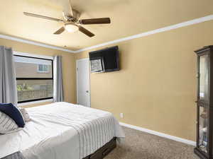 Bedroom featuring carpet, ceiling fan, a textured wall, and ornamental molding