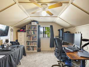 Office space with vaulted ceiling, carpet flooring, and a ceiling fan
