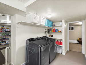 Washroom featuring washer and dryer, a textured ceiling, and light colored carpet