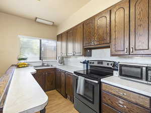 Kitchen with appliances with stainless steel finishes, light countertops, decorative backsplash, and light wood-type flooring