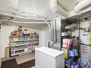 Basement with water heater and white fridge
