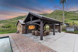 Patio terrace at dusk featuring an outdoor living space, a gazebo, a hot tub, and a mountain view