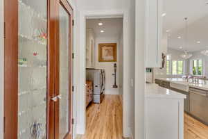 Hall with washer and dryer, light wood-style flooring, a chandelier, a sink, and recessed lighting