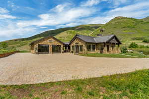 View of front facade featuring a standing seam roof, stone siding, a mountain view, and metal roof