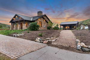 View of front of property with a standing seam roof, stone siding, a chimney, and metal roof