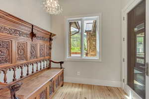 Mudroom with wood finished floors, a chandelier, and baseboards