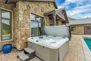 View of patio / terrace with a hot tub and a pool