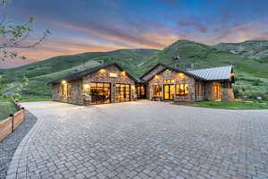 View of front of home with stone siding, curved driveway, an attached garage, a standing seam roof, and a mountain view