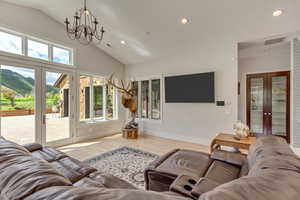Living area with french doors, a chandelier, wood finished floors, recessed lighting, and high vaulted ceiling