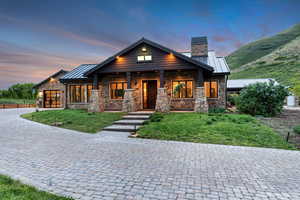 View of front of home with stone siding, a standing seam roof, and a chimney
