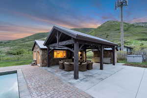 View of patio / terrace featuring a gazebo, an outdoor living space, a hot tub, a mountain view, and an outdoor pool